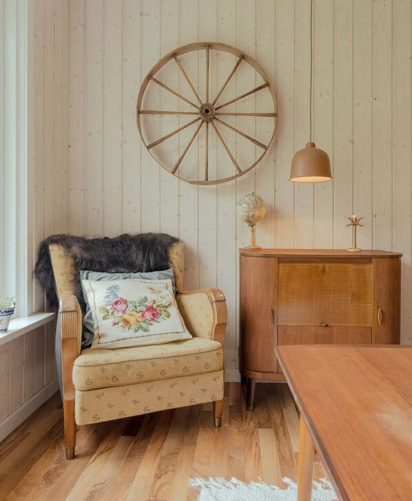 Une chaise en bois avec un coussin à motifs floraux, un meuble en bois et une lampe en forme de globe.