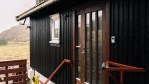 A wooden building with a dark exterior, a wooden door with glass panels, and a small window. - Unique Location - Bodanes - Hoydalar - 6 Br Villa (Hoyvík)