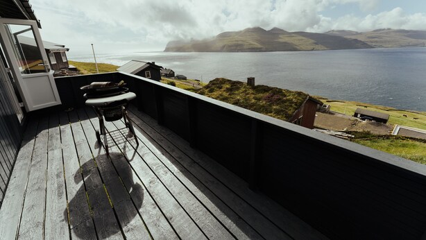 A wooden deck with a view of the sea and hills.