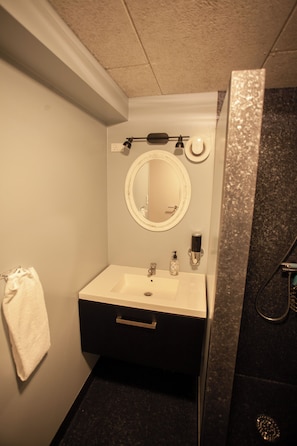 A compact bathroom with a white sink, a mirror, and a towel hanging on the wall.
