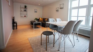 Uma sala de estar moderna com área de jantar, com um sofá, uma mesa de centro e uma mesa de jantar com cadeiras.