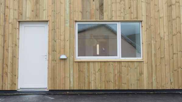 A wooden building facade with a white door and a window.