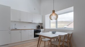 A modern kitchen with white cabinets, a wooden countertop, and a dining area with a white table and wooden chairs.