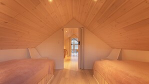 A cozy attic bedroom with two beds, wooden ceiling, and a view of the living area through a doorway. - Unique Boathouse - Central - Kajak - Fitness (Strendur)