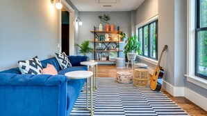 A modern living room with a blue sofa, round coffee table, and a guitar. - Private Suite in Historic Austin B&b: Sleeps 2! (Austin)
