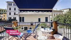 Eine Terrasse mit Gartenmöbeln, einer Pergola und Blick auf ein Gebäude mit Balkonen.