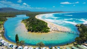 Zona costera con playa, aguas cristalinas y un puente que conecta la tierra.