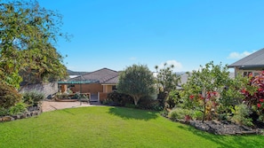 A residential property with a well-maintained lawn, a brick house, and a garden with various plants and trees.