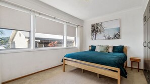 Una camera da letto con un letto, una finestra, un quadro e un armadio.