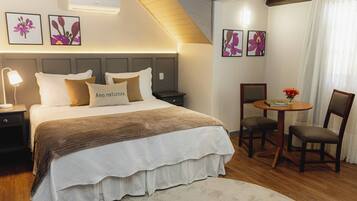 Quarto com cama, mesas de cabeceira, uma mesa redonda com cadeiras e ar condicionado na parede.
