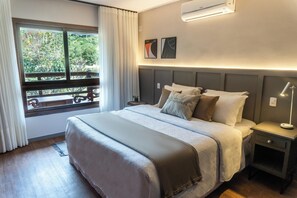 A modern hotel room with a large bed, a nightstand, a lamp, and a window with curtains.