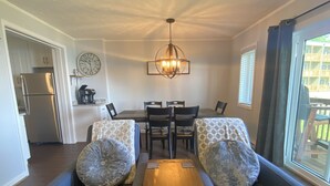 Een woonkamer met een zithoek, een salontafel en een eethoek met stoelen en een tafel.