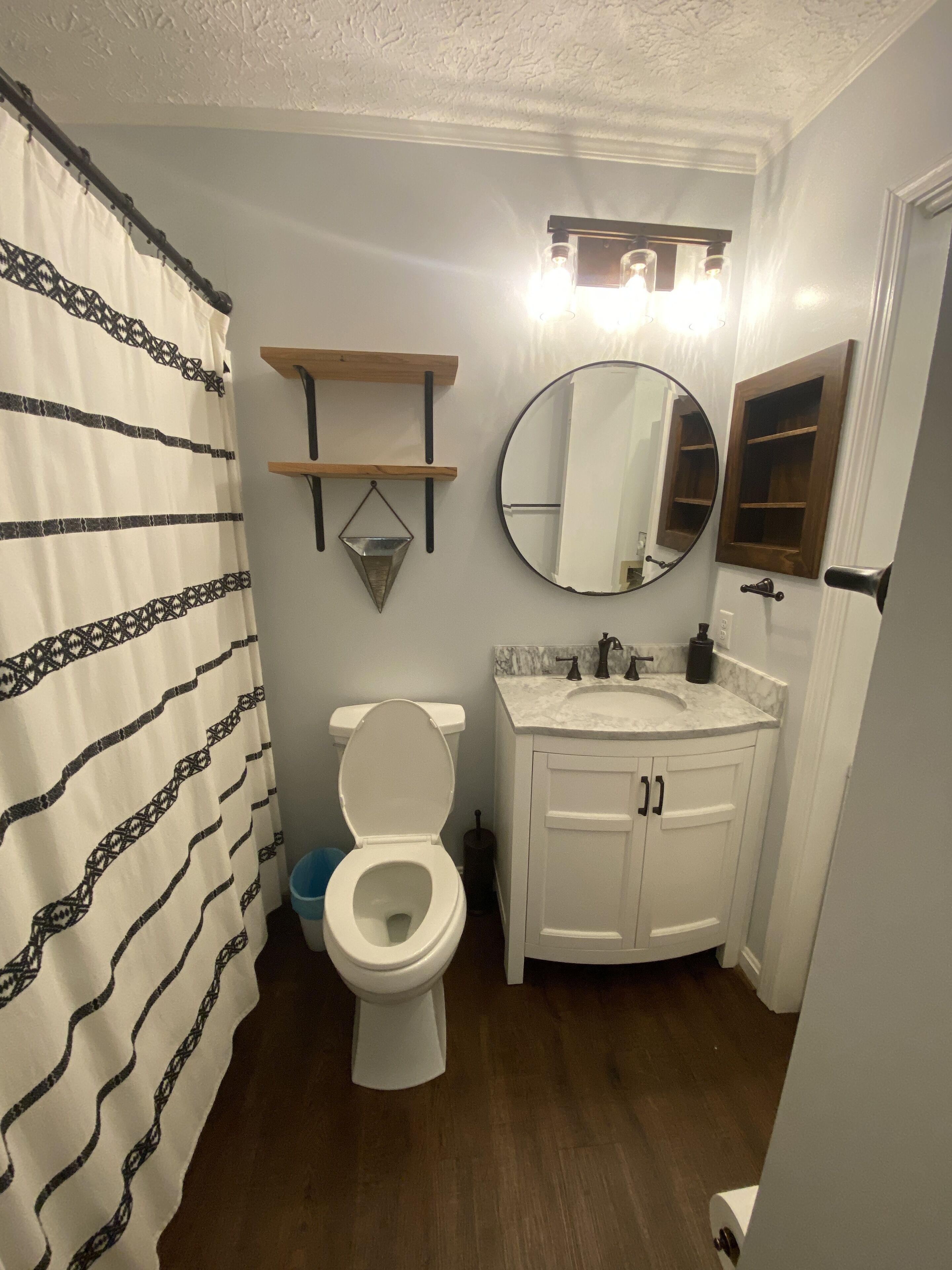 A bathroom with a toilet, a sink, a mirror, and a shower curtain.