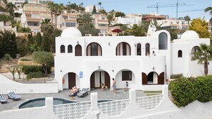 A white building with multiple arches and a pool area with lounge chairs. - Villa Levante Montiboli by Buccara (Villajoyosa)