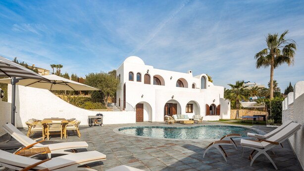 A pool area with lounge chairs, a table, and a building with arched windows. - Villa Levante Montiboli by Buccara (Villajoyosa)