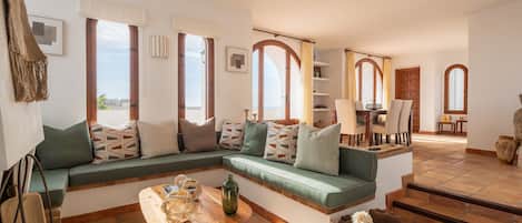 A spacious living area with a green sofa, wooden coffee table, and a view of the outdoors.