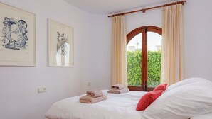A bedroom with a bed, pillows, a window with curtains, and two framed artworks on the wall. - Villa Levante Montiboli by Buccara (Villajoyosa)