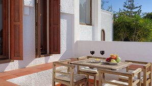 A wooden table with two wine glasses and a bowl of fruit on a terrace with white walls and wooden shutters. - Villa Levante Montiboli by Buccara (Villajoyosa)