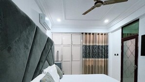 A modern bedroom with a large bed, a ceiling fan, and a wardrobe. - Mercy Royal Heights (Kumasi)