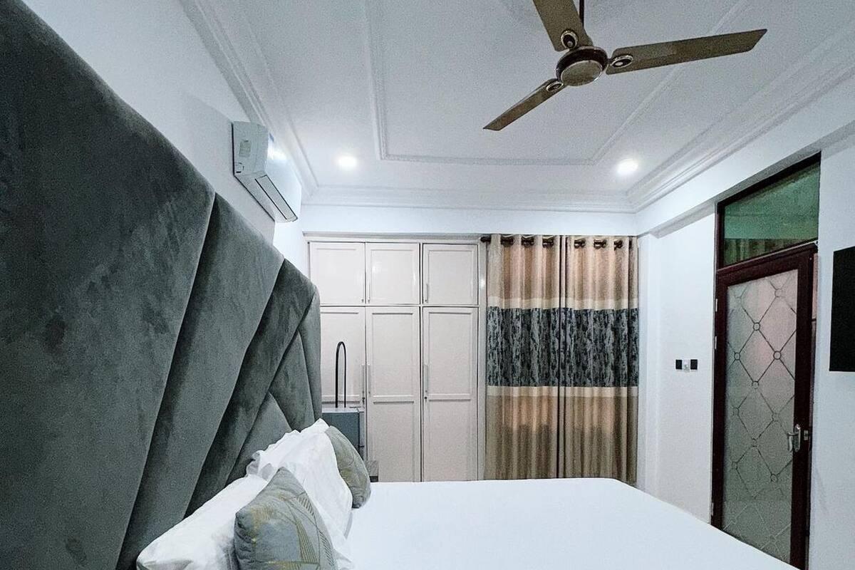 A modern bedroom with a large bed, a ceiling fan, and a wardrobe.