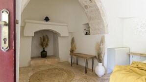 A cozy room with a stone archway, a fireplace, a woven rug, and a bench.