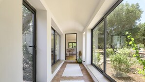 A corridor with large windows, a view of the outdoors, and a door leading to another room.