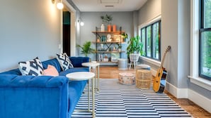 Una sala moderna con un sofá azul, una mesa redonda de centro y una guitarra.