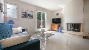 A modern living room with a sofa, glass coffee table, television, and fireplace.