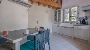 A kitchen with white cabinets, a wooden ceiling, and a dining area with a table and chairs.