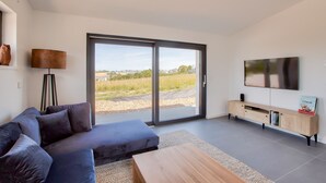 En moderne stue med sofa, sofabord og fjernsyn på et træskab.