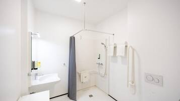 Un baño moderno con ducha, lavamanos y espejo.