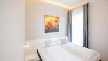 Ein Hotelzimmer mit Bett, einem Bild an der Wand und einem Fenster mit Vorhängen.