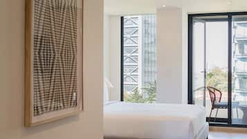 Een moderne slaapkamer met een groot bed, een bankje en stadszicht door grote ramen.