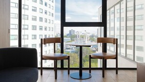 A modern room with two leather chairs around a small table, large windows offering a city view. - Crisol Suites Condesa (Mexico City)