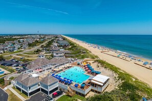 A coastal resort with a large swimming pool, beach access, and residential buildings.