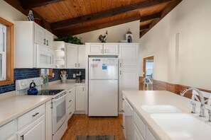 A kitchen with white cabinets, a stainless steel refrigerator, a microwave, and a coffee maker.