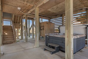 A wooden structure with a hot tub, a staircase, and a covered area with a view of the outdoors.