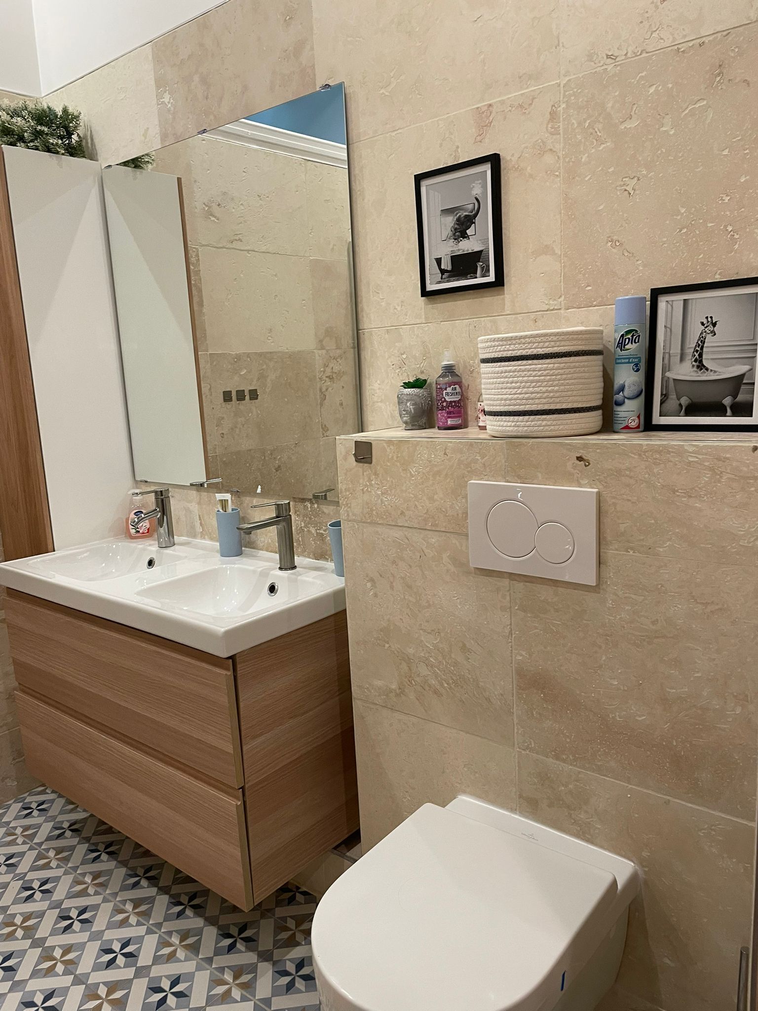 Ein Badezimmer mit doppeltem Waschbecken, Toilette, Spiegel und Ablage für Toilettenartikel.