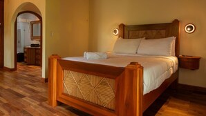Una cama de madera con cabecera geométrica, dos mesitas de noche con lámparas de pared y suelo de madera.