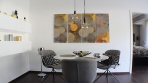 Uma área de jantar moderna com uma mesa redonda, duas cadeiras e uma grande pintura abstrata acima.