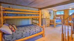 Een blokhutinterieur met een stapelbed, een bureau en een trap.