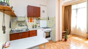 Une cuisine de taille réduite, avec des meubles en bois, un plan de travail blanc, une cuisinière et un évier.