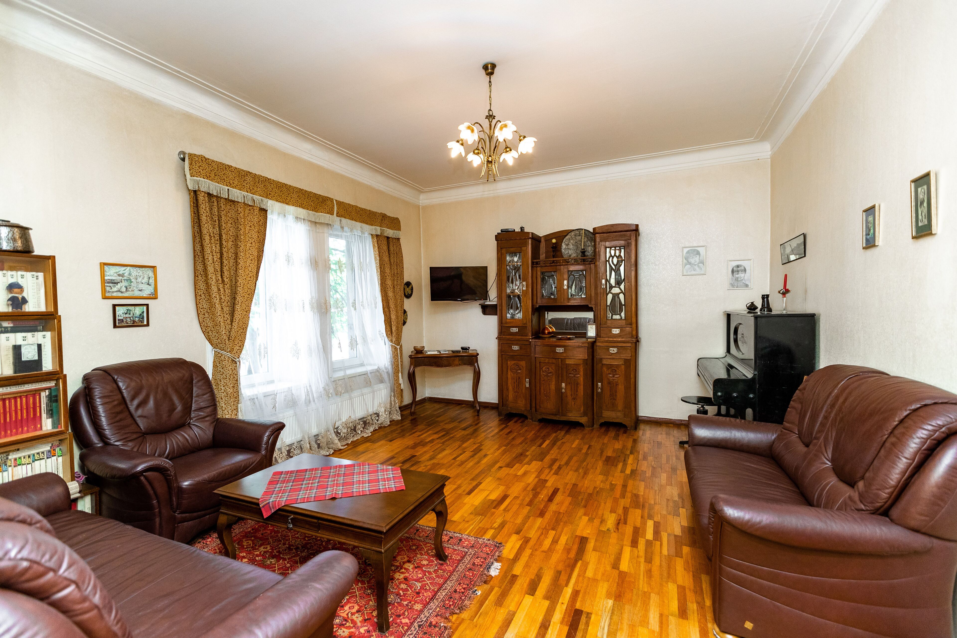 A living room with leather sofas, a wooden coffee table, a television, and a cabinet with decorative items.