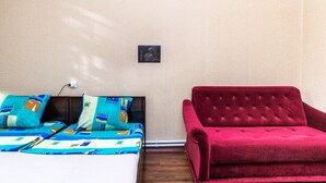 Une pièce avec un lit, un canapé rouge et un interrupteur fixé au mur.