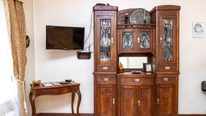 Une pièce avec un meuble en bois, un téléviseur fixé au mur et une petite table sur laquelle se trouvent un bol et des livres.