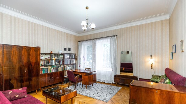 Un salon avec une table basse en bois, un canapé rouge, un meuble en bois et une bibliothèque.