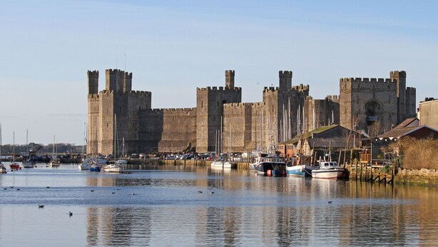 Un château historique, doté d’un fossé, entouré de bateaux et bordé de bâtiments situés au bord de l’eau.