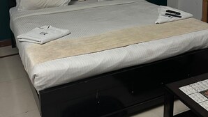 A neatly made bed with white linens, a dark headboard, and a small bedside table with a remote control. - iROOMZ Hotel Shree Jagannath (Hyderabad)