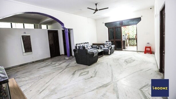 A spacious living area with a marble floor, a sofa set, a ceiling fan, and a view through an open archway to the outside. - iROOMZ Hotel Shree Jagannath (Hyderabad)