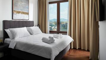 A hotel room with a bed, a view of a cityscape, and a painting on the wall.